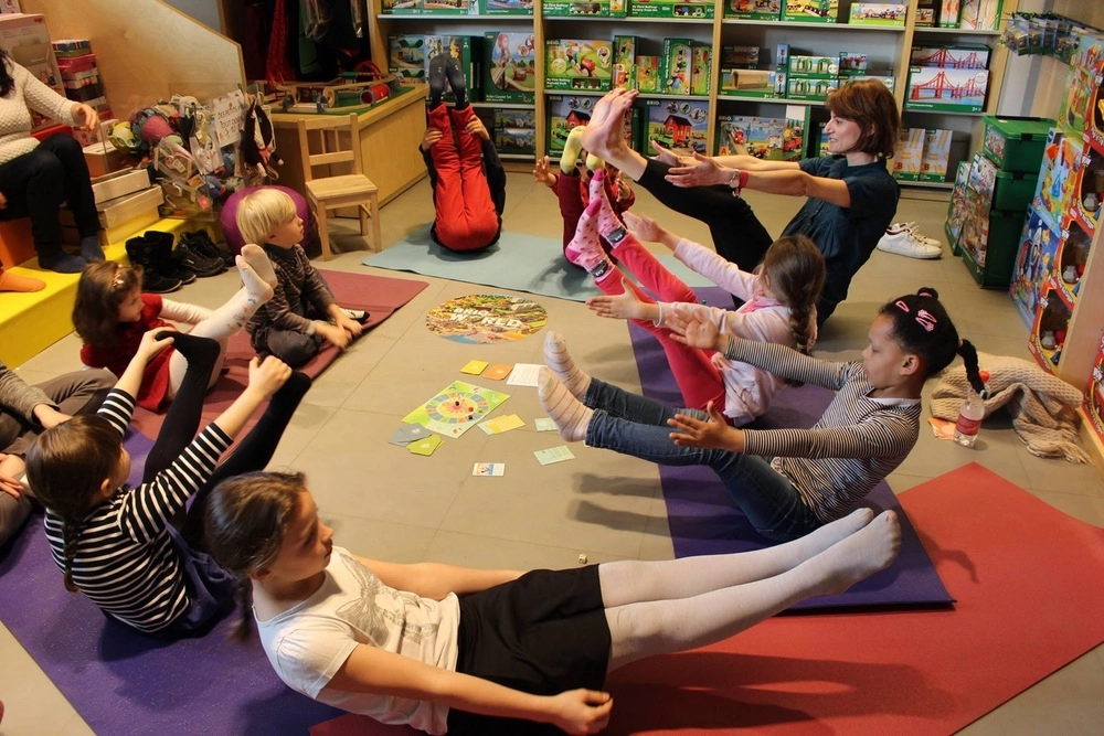 Animatrice de yoga guidant un groupe d'enfants avec le jeu YogaKiddy